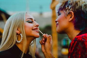 Young woman applying lipstick on her friend lips.