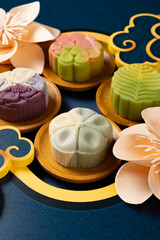 angle view colorful flower shape snowy mooncakes with Chinese decorations at vertical composition