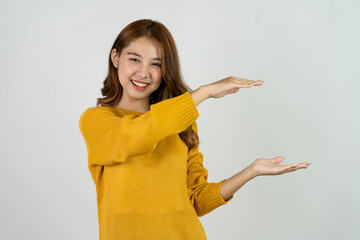 Excited Asian woman raising hands gesture on isolated background, promo advertisement concept Cheerful teenage girl in yellow shirt standing in white room