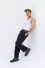 Isolated cutout studio shot Asian vintage classy mustache with neck arms hands tattoos male fashion model in casual fashionable sleeveless shirt cap boots posing standing on white background.