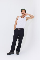 Isolated cutout studio shot Asian vintage classy mustache with neck arms hands tattoos male fashion model in casual fashionable sleeveless shirt cap boots posing standing on white background.