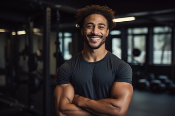 Fototapeta premium Smiling portrait of a happy young male african american fitness instructor in an indoor gym
