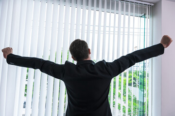 Back view businessman stretching both arms feeling tired from overworked in office
