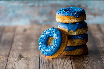 A stack of blue decorated donuts with one leaning in front.