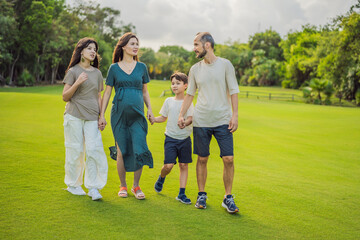 A loving family enjoying a leisurely walk in the park - a radiant pregnant woman after 40, embraced by her husband, and accompanied by their adult teenage children, savoring precious moments together