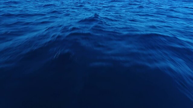 Low angle, deep blue ocean water texture pattern with sun defining surface ripples, aerial