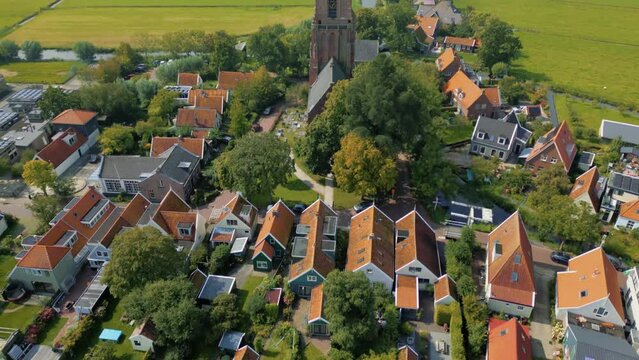 Aerial above typical Dutch village houses at waterfront tilt up to church