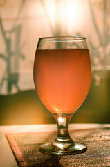 Fresh glass of pils beer. Beer pint on the table at sunset, closeup glass of  light beer and blurred window  background