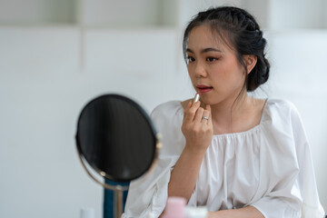 Asian female video blogger to review cosmetics. Influencer beauty blogger broadcasts makeup tools, lipsticks, powders, buffs, perfumes how to do makeup for social followers in the office