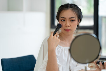 Asian female video blogger to review cosmetics. Influencer beauty blogger broadcasts makeup tools, lipsticks, powders, buffs, perfumes how to do makeup for social followers in the office