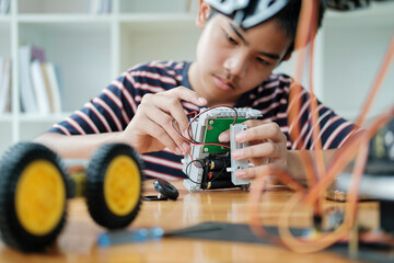 Asian teenager doing robot project in science classroom. technology of robotics programing and STEM...