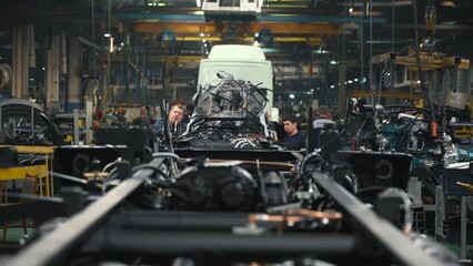 Automotive Equipment Production Facility.  A Production Line is filled with multiple Vehicles Parts at the Automotive Factory. Workers are Supervising the Manufacturing Process at Automotive Plant.