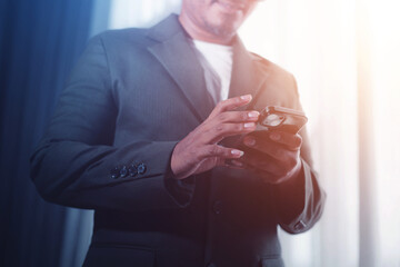Businessman using smartphone, success after monthly meeting, corporate window background, success...