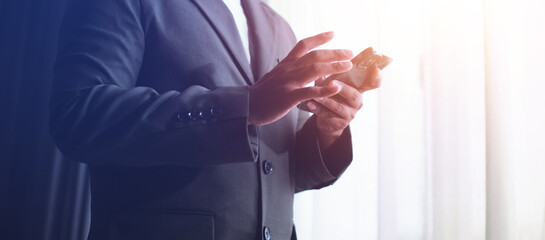 Fototapeta premium Businessman using smartphone, success after monthly meeting, corporate window background, success concept