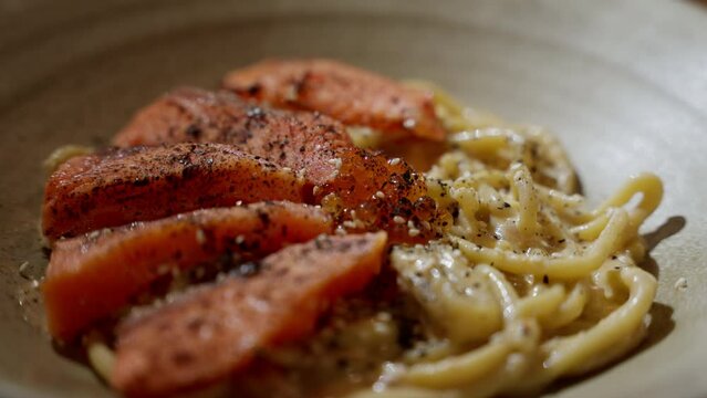 Elegant salmon spaghetti bathed in captivating moody lighting. Each tender bite of salmon is beautifully accentuated, while the pasta glistens in rich, savory sauce. luxurious dining experience.