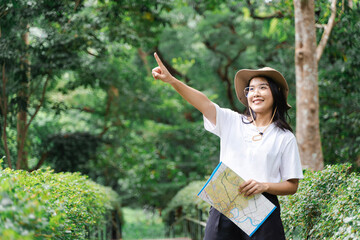 Asian woman explorer hold paper map to survey natural route , point finger up. Concept, travelling, nature exploration. Ecology study. Pastime activity.