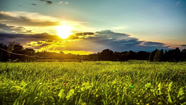 Colorful low angle sunset time lapse over a grassy countryside meadow