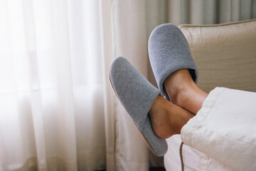 Closeup of a woman wearing slippers while laying on sofa