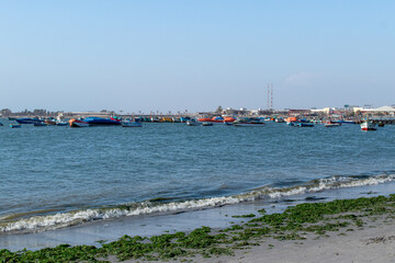 Fototapeta na wymiar Muelle en la Mar con botes y personas a la orilla de la playa