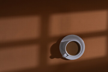 Coffee and cookies on brown background with window shadow, aesthetic morning background concept

