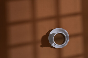 Coffee and cookies on brown background with window shadow, aesthetic morning background concept
