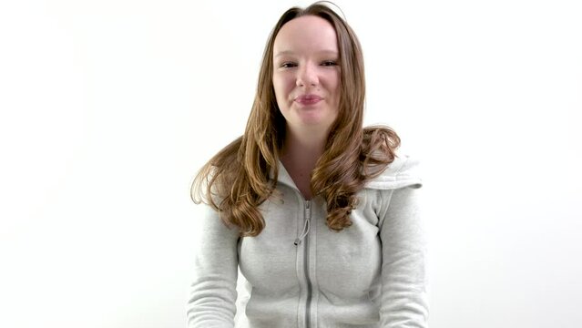 Caucasian attractive girl over white wall making unimportant gesture while lifting the shoulders wearing pastel shirt. High quality 4k footage