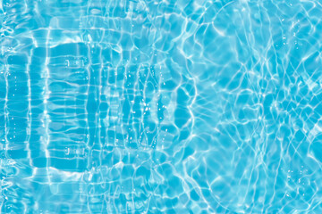 Blue water with ripples on the surface. Defocus blurred transparent blue colored clear calm water surface texture with splashes and bubbles. Water waves with shining pattern texture background.