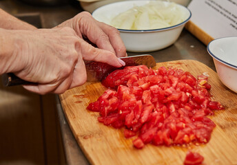 Chef cuts the tomatoes into small cubes for cooking