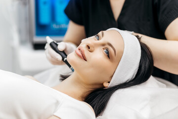 Cosmetology clinic. Professional female cosmetologist doing hydrafacial procedure while being a...