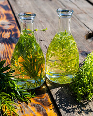 Vegetable oil in bottles on the table. Composition of bottles with rosemary and thyme oil. Fry the rosemary and thyme sprigs in olive oil. Bottles of oil on a wooden table. Selective focus. 