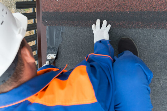 a worker in uniform and helmet, carrying out work to eliminate roof leaks, close-up