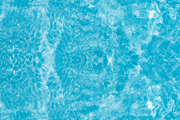 Blue water with ripples on the surface. Defocus blurred transparent blue colored clear calm water surface texture with splashes and bubbles. Water waves with shining pattern texture background.