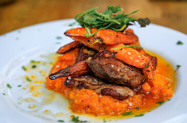 Seared duck breast or magret de canard au jus with mashed and roasted carrots, garnished with arugula at a French restaurant, Old Town of Nice, France