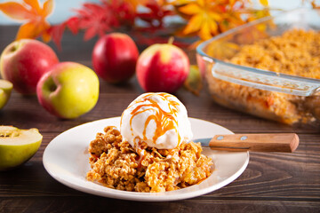 Homemade apple cramble crisp cake on white plate with autumn leaves on the background