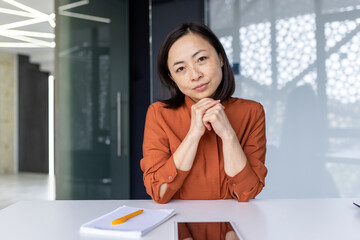 Portrait of serious confident business woman, Asian looking thoughtfully at camera, listening to...