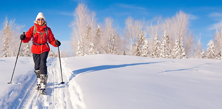 Mature Woman Cross Country Skiing On A Sunny Winter's Day. Concept Of Senior Exercise And Activities. Shallow Field Of View With Copy Space.