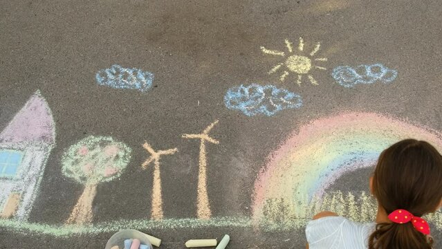 A child draws a rainbow on the pavement. Selective focus.