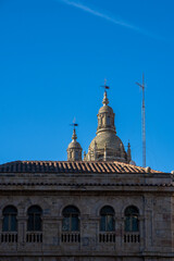 Fototapeta na wymiar Romanesque domes of the old cathedral of Salamanca behind the facade and roof of a classical and monumental building. Castilla y León, Spain.