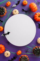 Spine-chilling Halloween scene: Vertical top view shot of thematic setup, eerie insects including spiders, pumpkins, green spiderweb, bats against violet background, open circle for text incorporation