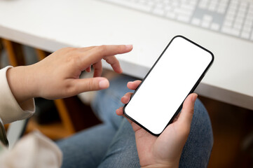 Close-up image of a female in casual clothes using her smartphone at her desk in the office.