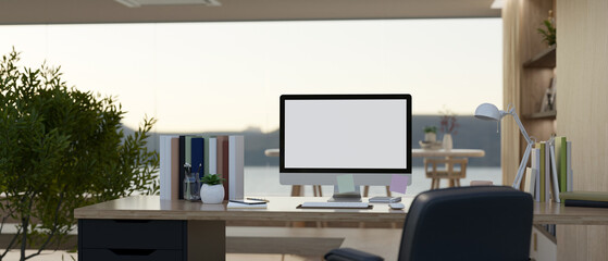 A modern computer desk in a modern working room or home office with a large glass window wall.