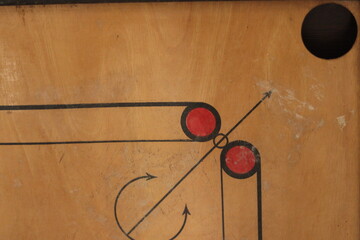 A closeup shot of an old Carrom board with scratches and focus on the hole of the carrom board 