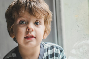 Little boy sitting on the window sill and  playing with lots of colorful plastic blocks constructor. Boy playing with construction blocks at kindergarten. 