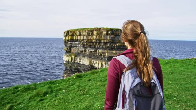 Woman walking towards sea stack at Dun Briste