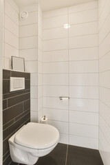a white toilet in a black and white tiled bathroom with dark tiles on the floor, walls and wallpapers