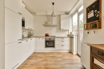 a kitchen with wood flooring and white cabinetd cupboards on the wall, an oven in the corner