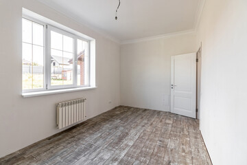 A room in a private house immediately after laying the floor, white unfinished walls and ceiling