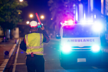 Security officers are using traffic batons to facilitate an ambulance at the accident site.