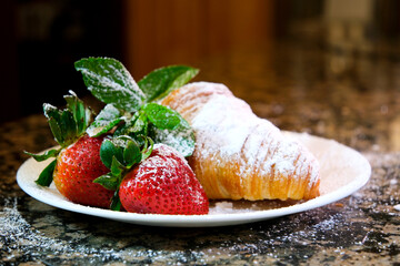 closeup of croissant sprinkled with powdered sugar with strawberries and mint leaves delicious dessert french breakfast restaurant serving cook at home decorate many different videos with strawberries