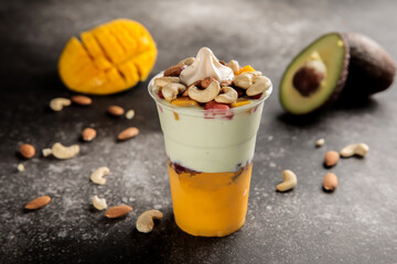 mango and avocado cocktail juice with strawberry, cream, almond and cashew nut served in glass...